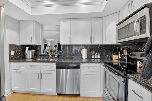 a kitchen with granite countertop white cabinets and stainless steel appliances