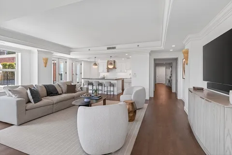a living room with furniture a flat screen tv and a refrigerator