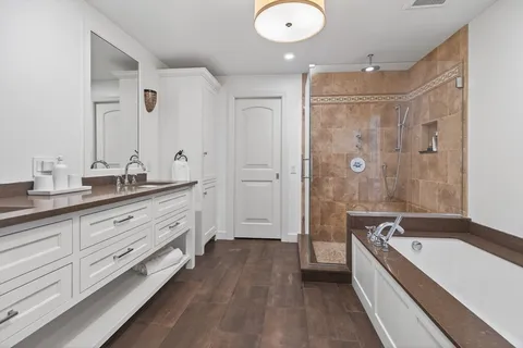 a spacious bathroom with a tub sink shower and mirror