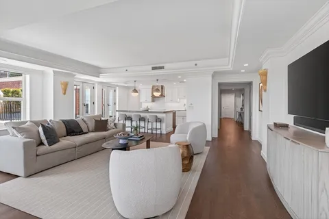 a living room with furniture a flat screen tv and a refrigerator