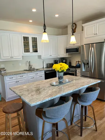a kitchen with stainless steel appliances granite countertop a table chairs sink refrigerator and microwave