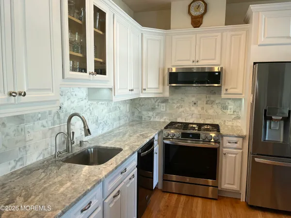 a kitchen with granite countertop a sink stainless steel appliances and cabinets