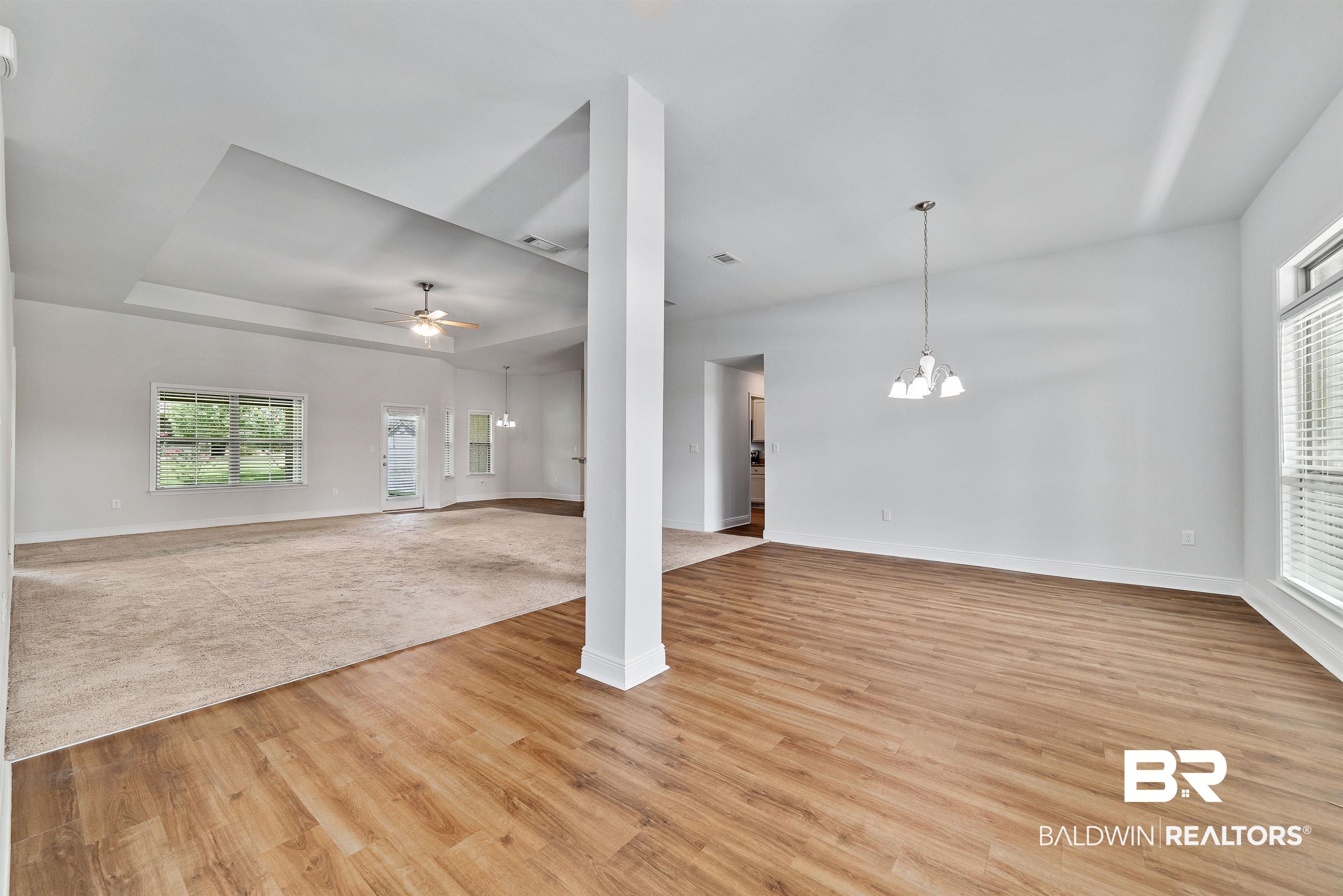 13155 Wishbone Court Foley, AL 36535 - Photo 10 of 39 Unfurnished living room with a tray ceiling, light carpet, and ceiling fan with notable chandelier