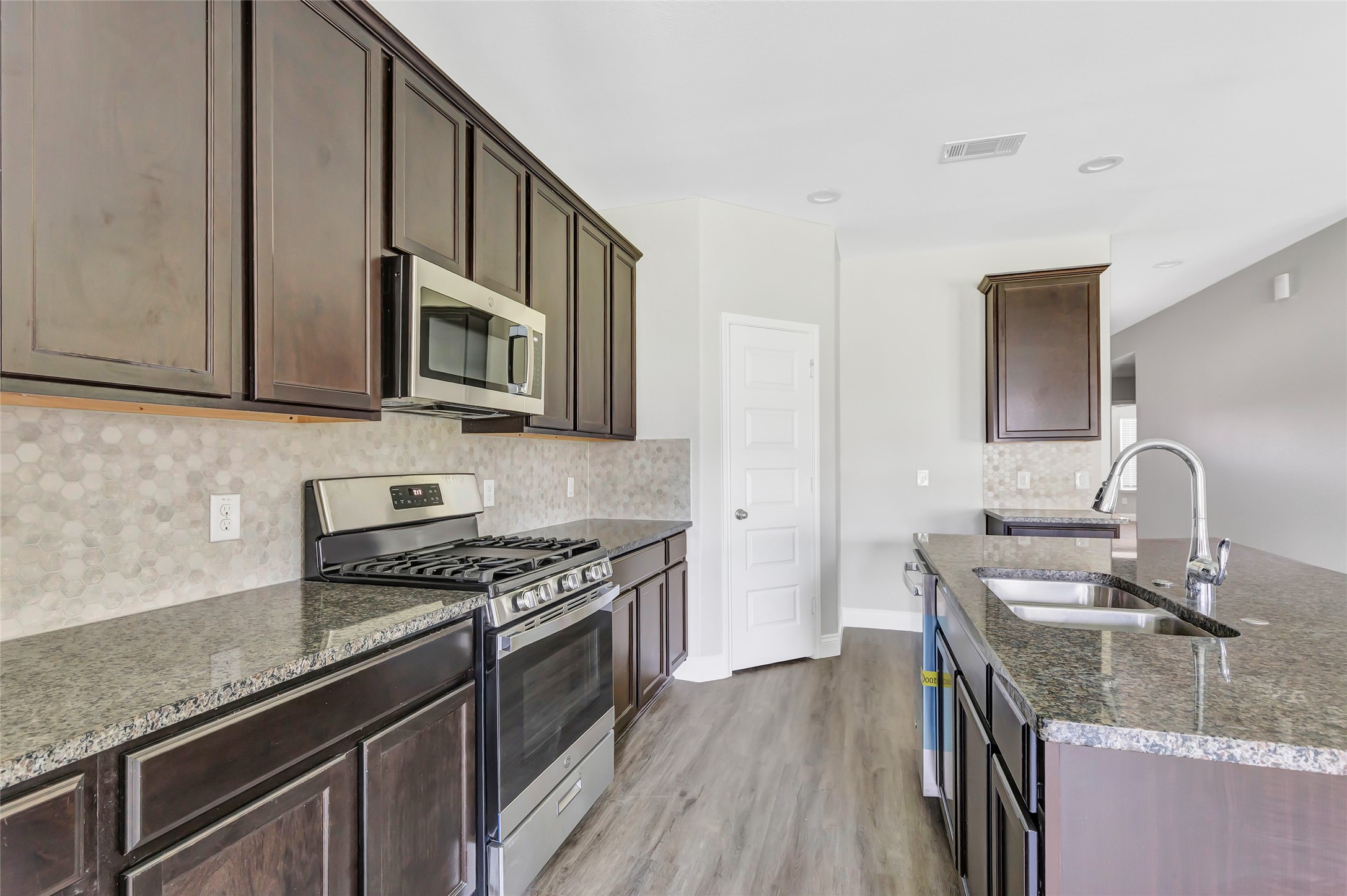 214 Kickapoo Drive Anahuac, TX 77514 - Photo 11 of 36 a kitchen with granite countertop a sink a stove and cabinets