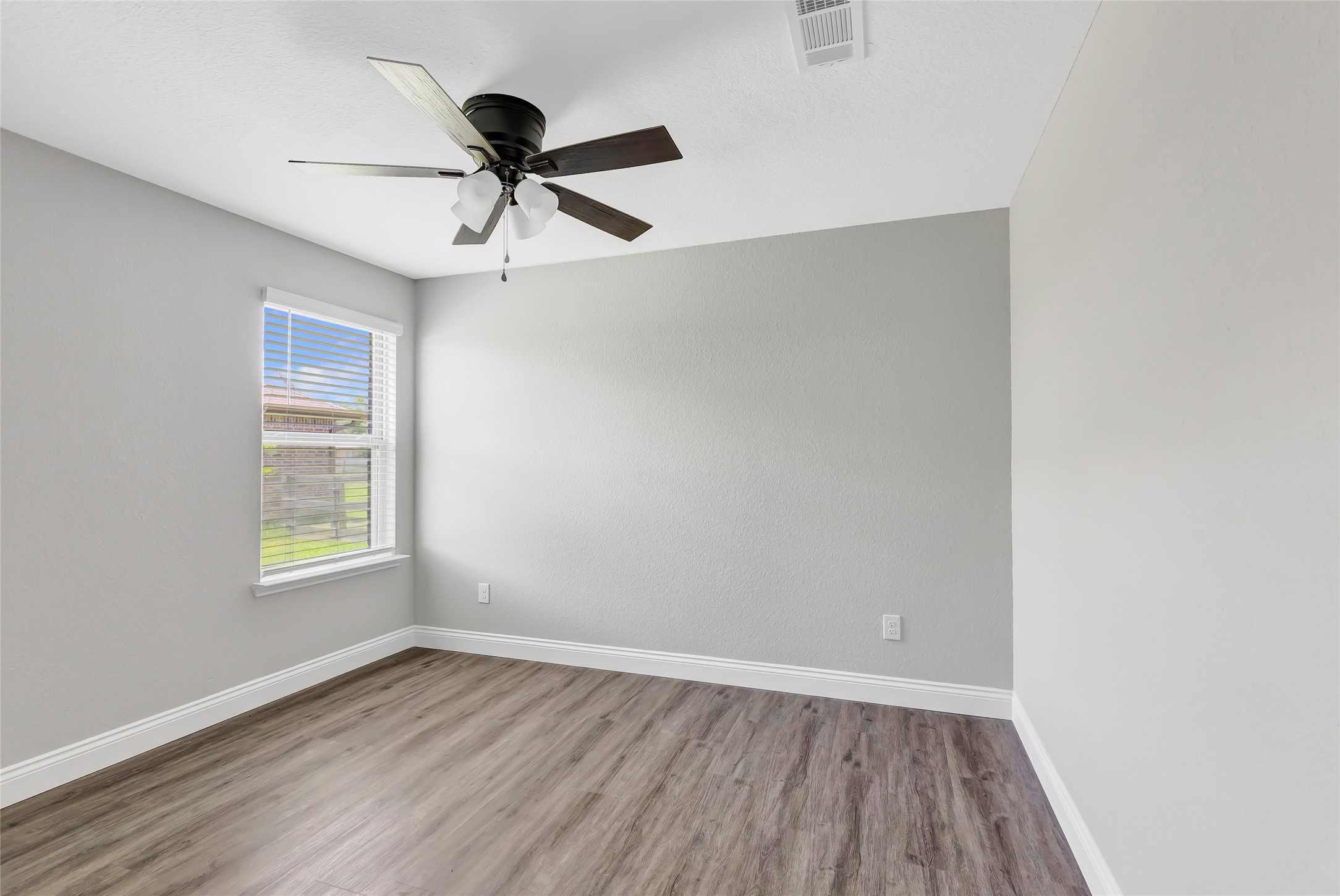 214 Kickapoo Drive Anahuac, TX 77514 - Photo 20 of 36 an empty room with wooden floor ceiling fan and windows