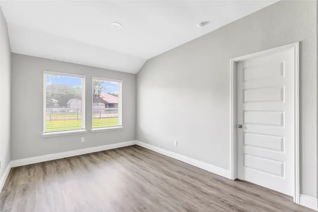 an empty room with wooden floor ceiling fan and windows