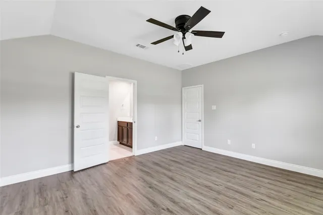 an empty room with wooden floor chandelier fan and windows