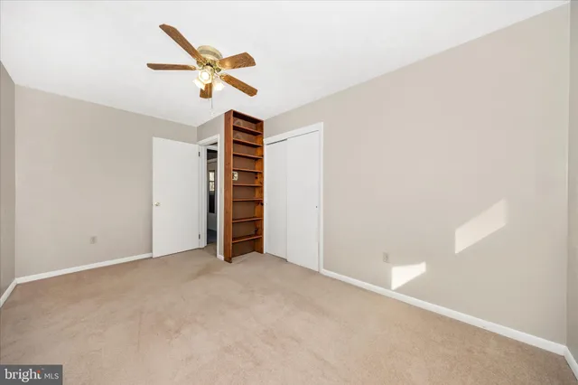 an empty room with closet and ceiling fan