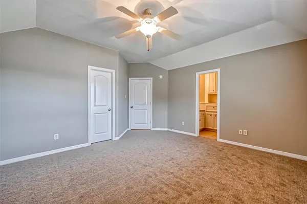 an empty room with a chandelier fan and windows