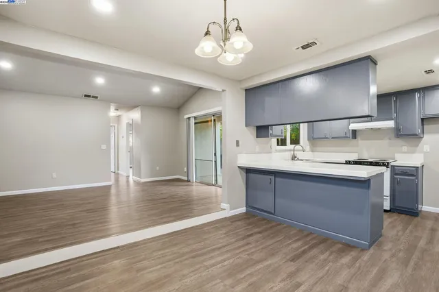 a large kitchen with kitchen island a sink stainless steel appliances and wooden floor