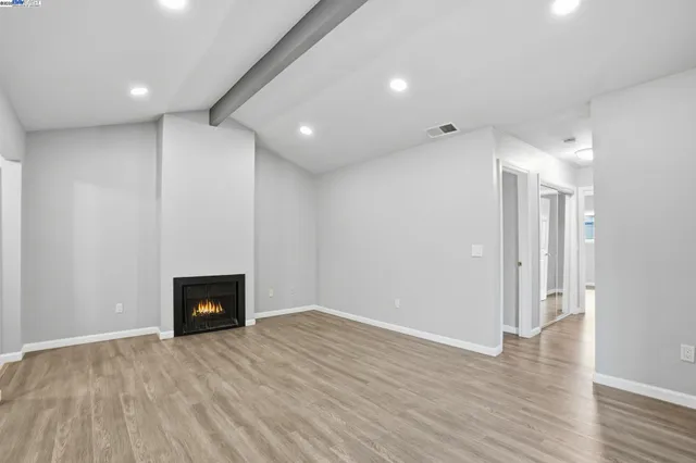 a view of empty room with wooden floor and a fireplace
