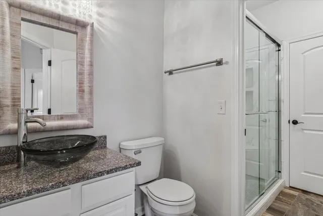 a bathroom with a granite countertop sink a toilet and shower