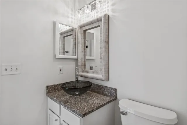 a bathroom with a granite countertop sink and a toilet