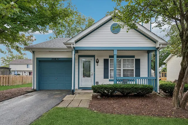 a view of a house with brick walls plants and large tree