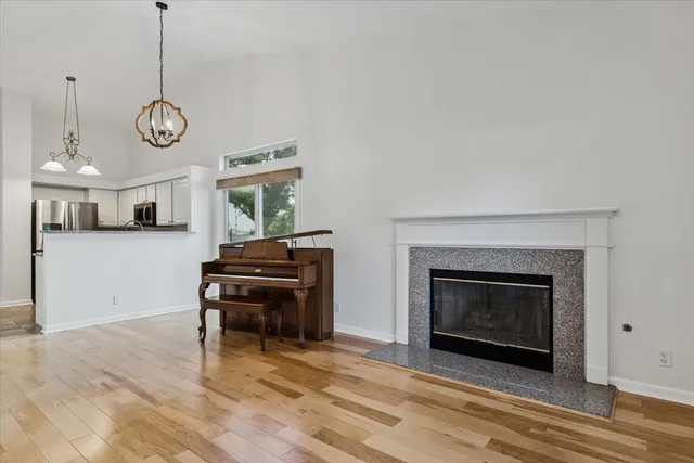 a view of an empty room with wooden floor fireplace and a window