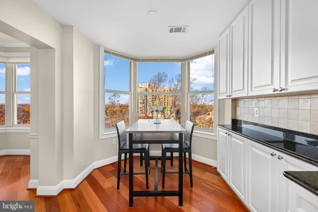 a kitchen with stainless steel appliances granite countertop a refrigerator a sink a stove a dining table and chairs