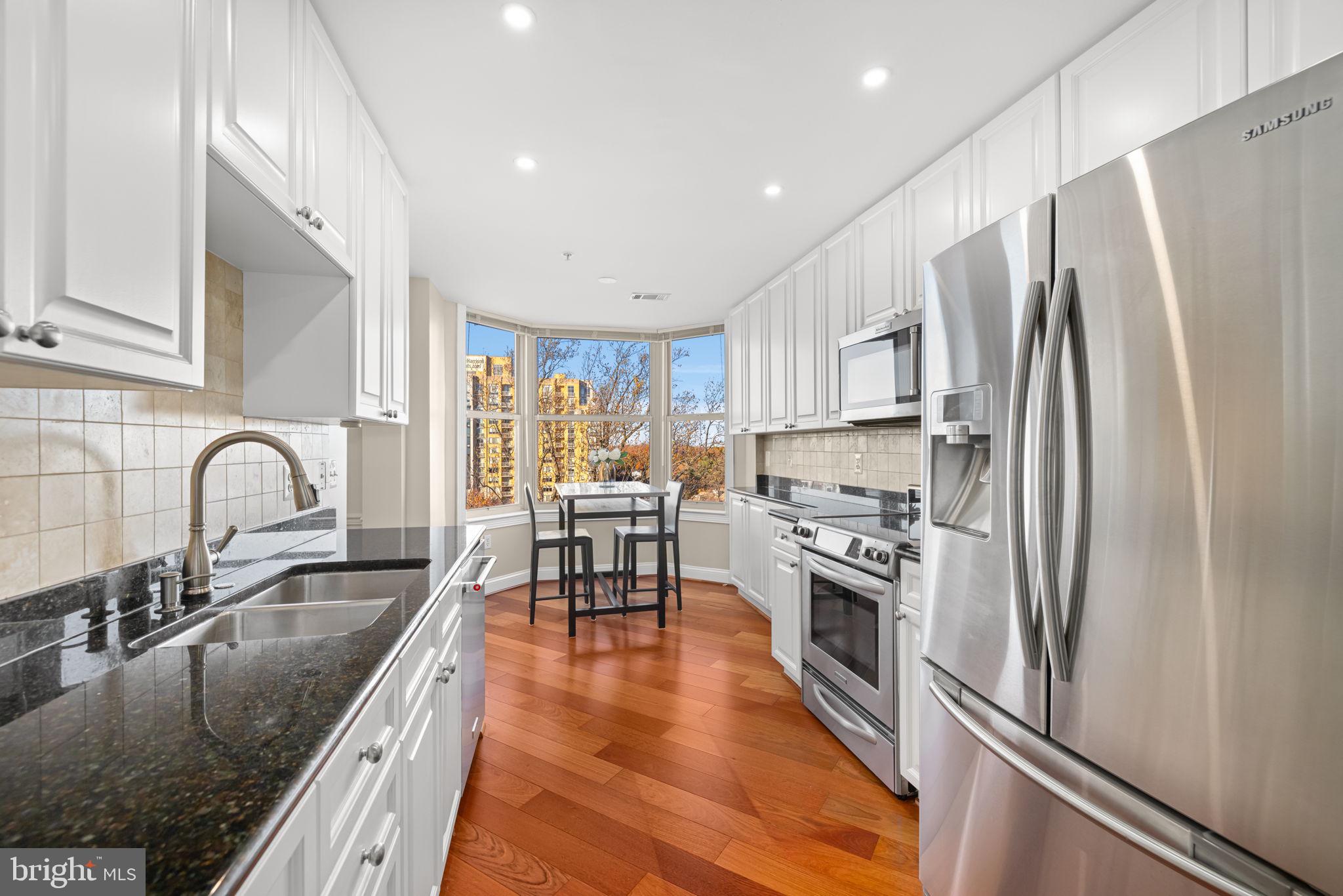 11776 Stratford House Place, Unit 907 Reston, VA 20190 - Photo 15 of 38 a kitchen with stainless steel appliances granite countertop a refrigerator a sink a stove a dining table and chairs