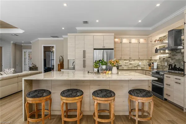 a kitchen with stainless steel appliances a table chairs sink and cabinets