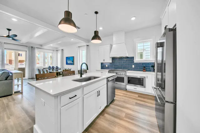 a large kitchen with stainless steel appliances kitchen island granite countertop a lot of counter space and a chandelier