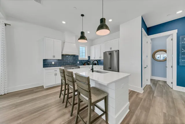 a kitchen with stainless steel appliances a dining table chairs and wooden floor