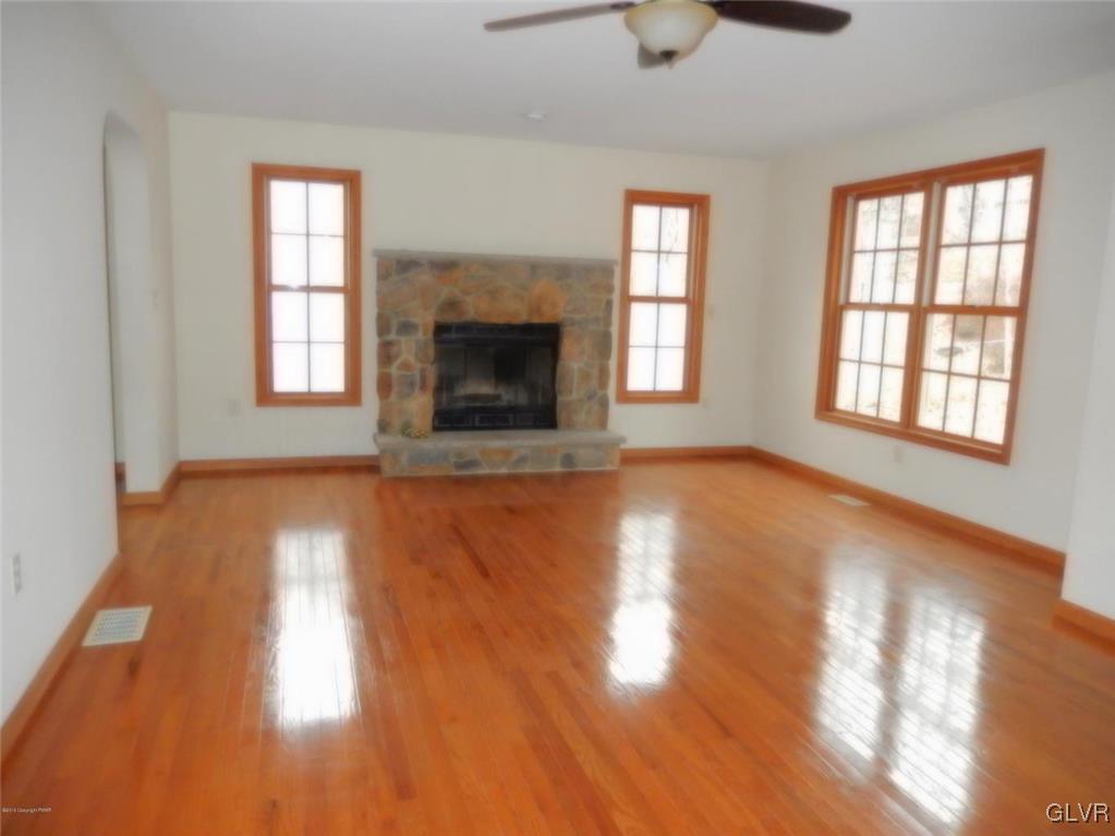 5886 Decker Road Bushkill, PA 18324 - Photo 4 of 15 an empty room with wooden floor fireplace and windows