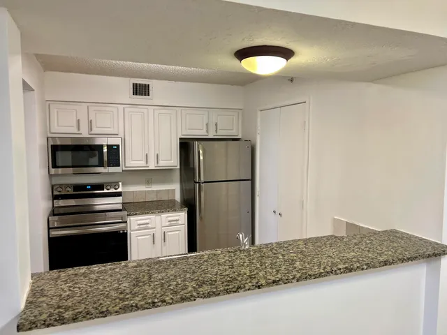 a kitchen with stainless steel appliances granite countertop a refrigerator sink and stove