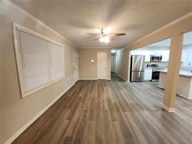 a view of a room with wooden floor kitchen view and a window