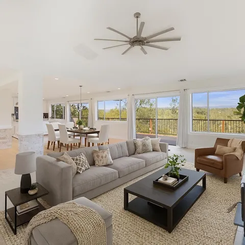 a living room with furniture a large window and a chandelier