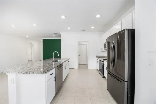 a kitchen with stainless steel appliances granite countertop a stove a refrigerator a sink and white cabinets
