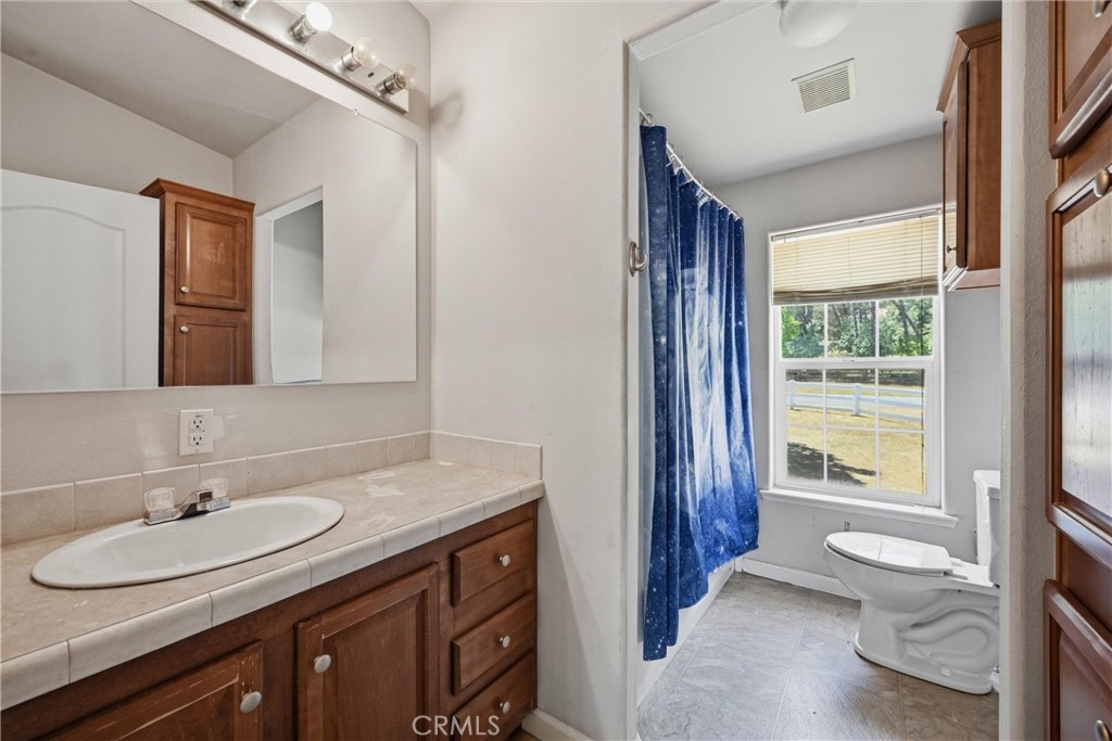 2860 Spring Valley Road Clearlake Oaks, CA 95423 - Photo 26 of 38 a bathroom with a granite countertop sink toilet a large mirror and shower
