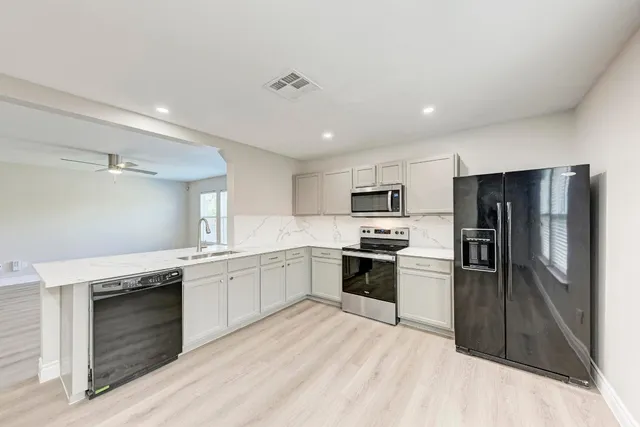 a large kitchen with cabinets wooden floor and stainless steel appliances