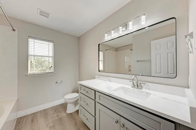 a bathroom with a sink a toilet and a large mirror