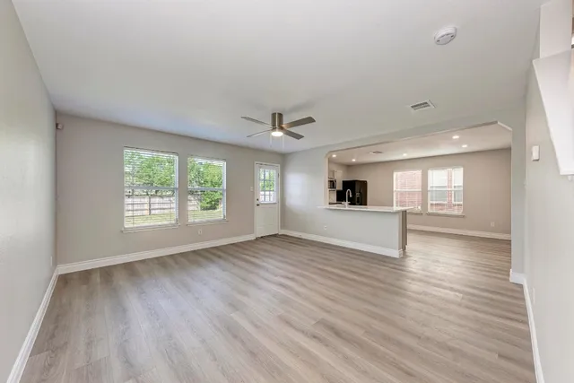 an empty room with wooden floor and windows
