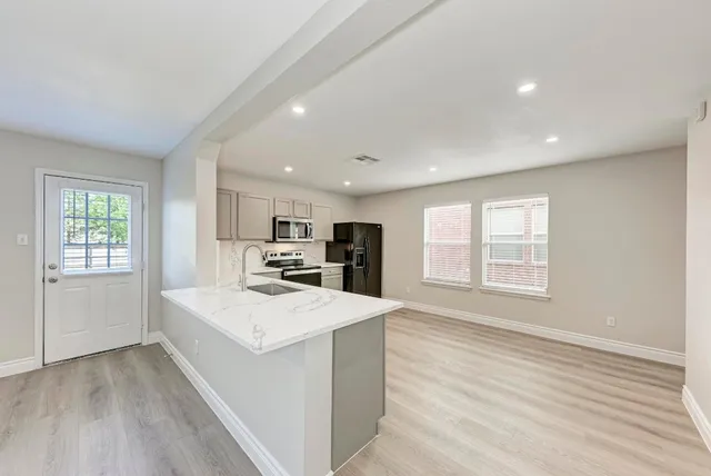 a large white kitchen with wooden floor and large window