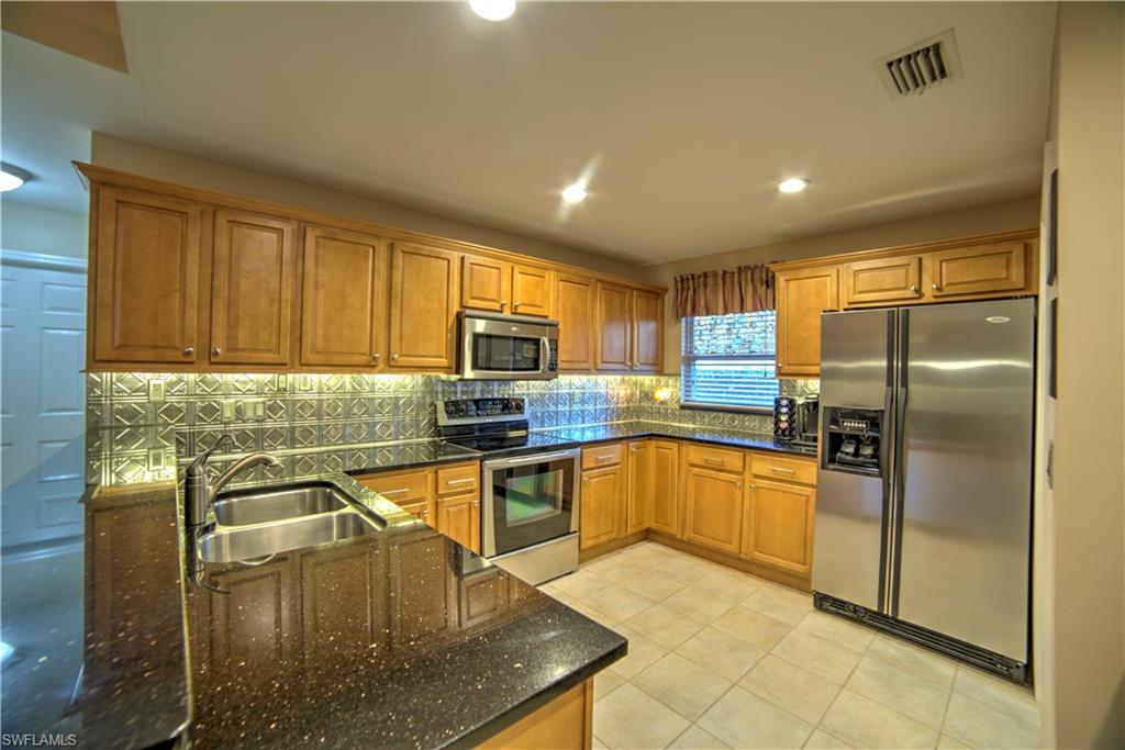 9143 Irving Road Fort Myers, FL 33967 - Photo 4 of 14 a kitchen with stainless steel appliances granite countertop a sink stove and refrigerator