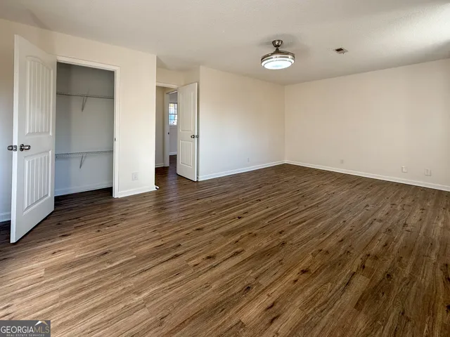 a view of empty room with wooden floor and white walls