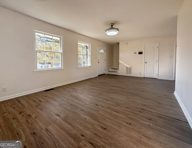an empty room with wooden floor and windows
