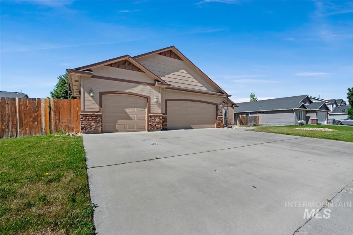 640 Southwest Miner Street Mountain Home, ID 83647 - Photo 7 of 35 Exterior featuring tan siding with brown trim, stone veneer accents, and multiple garage doors
