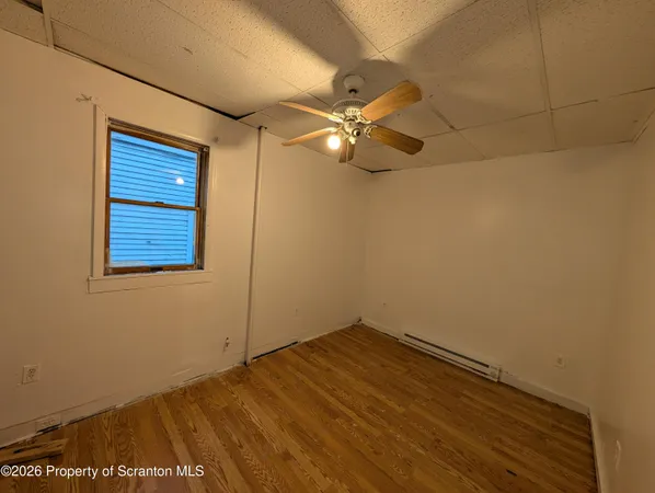 an empty room with a window and ceiling fan