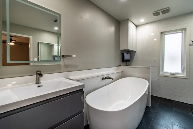 a bathroom with a white tub sink and mirror