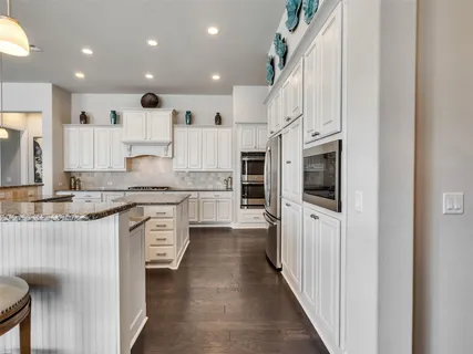 a large kitchen with stainless steel appliances kitchen island granite countertop a refrigerator and a stove top oven