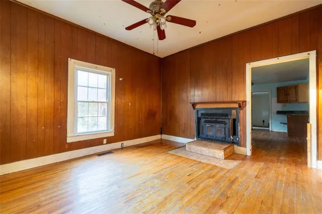 an empty room with windows fireplace and a chandelier fan