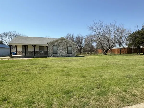 a view of a big house with a big yard and large trees