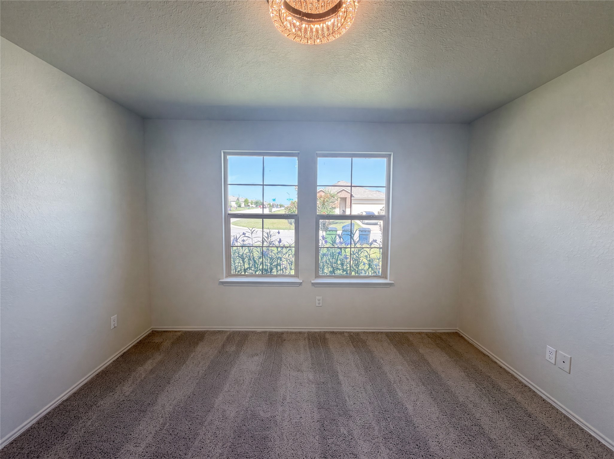233 Atwood Loop Jarrell, TX 76537 - Photo 8 of 15 Large double windows invite natural light across the textured walls and soft neutral carpeting.