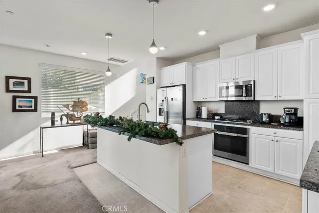 a kitchen with stainless steel appliances kitchen island granite countertop a stove and white cabinets