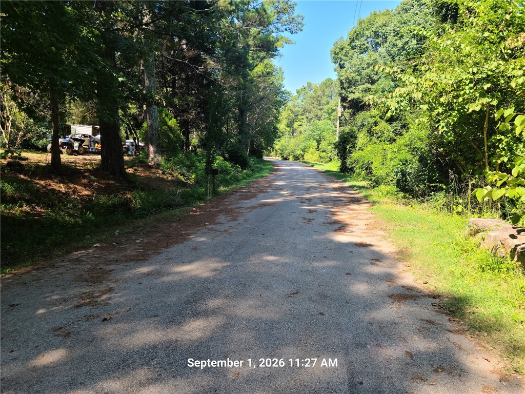 401 Miley Farm Road Cowpens, SC 29330 - Photo 1 of 1 Mature trees frame a quiet, paved road leading toward the property under clear blue skies.