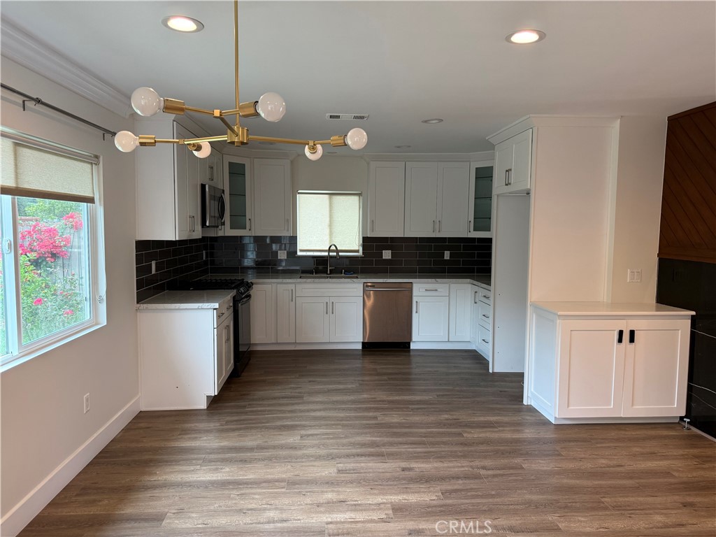 7459 Ruffner Avenue Van Nuys, CA 91406 - Photo 9 of 20 a kitchen with stainless steel appliances kitchen island granite countertop a stove a sink and a microwave