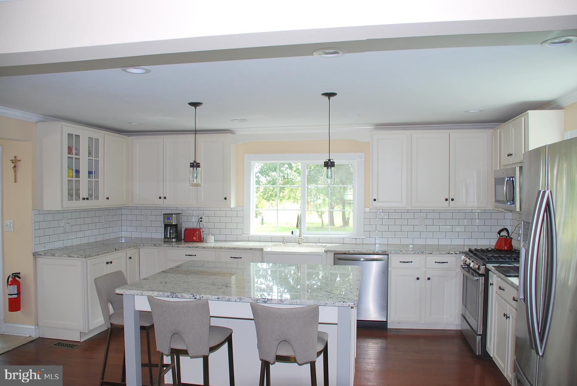 a kitchen with stainless steel appliances granite countertop a sink a counter top space and a window