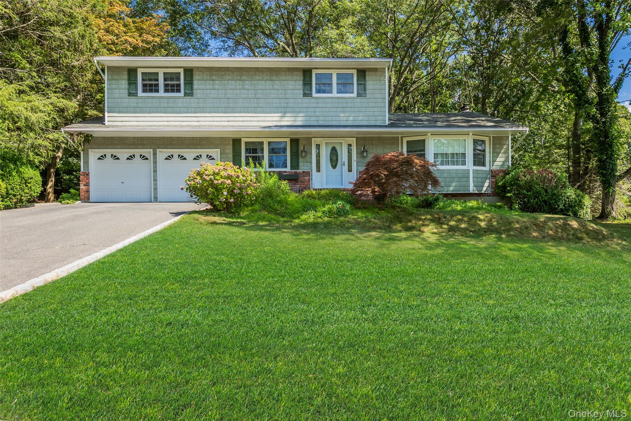 a front view of a house with a garden and yard