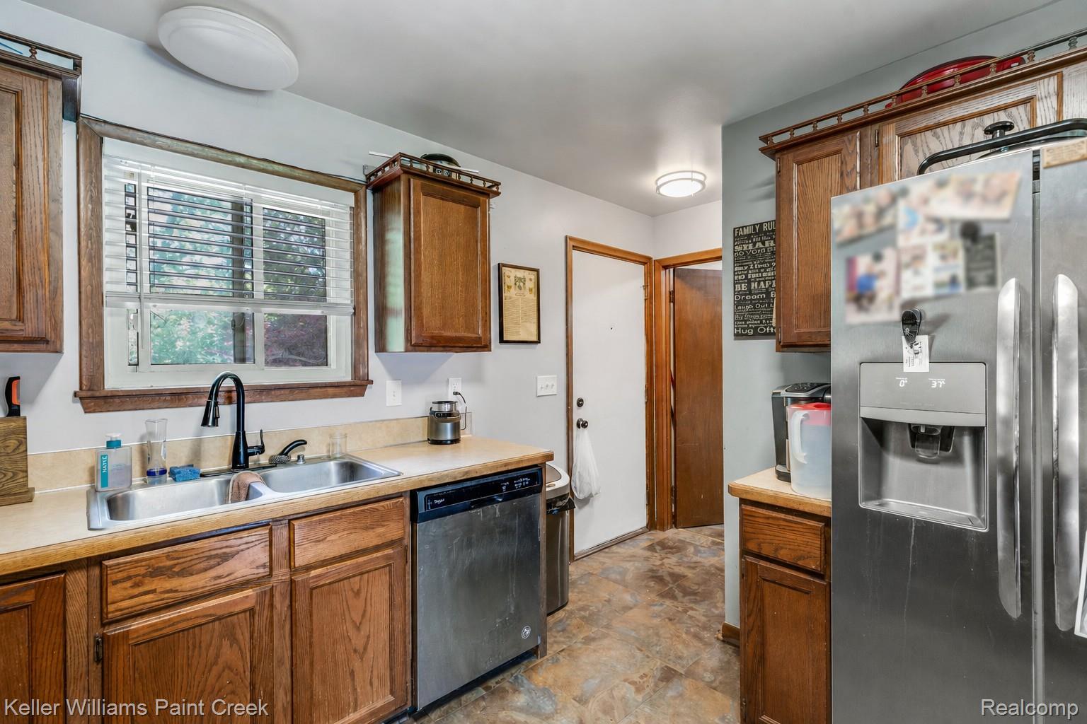6459 East Potter Road Davison, MI 48423 - Photo 11 of 22 Kitchen featuring a stainless steel double basin sink with a matte black faucet, wood cabinetry, and laminate countertops